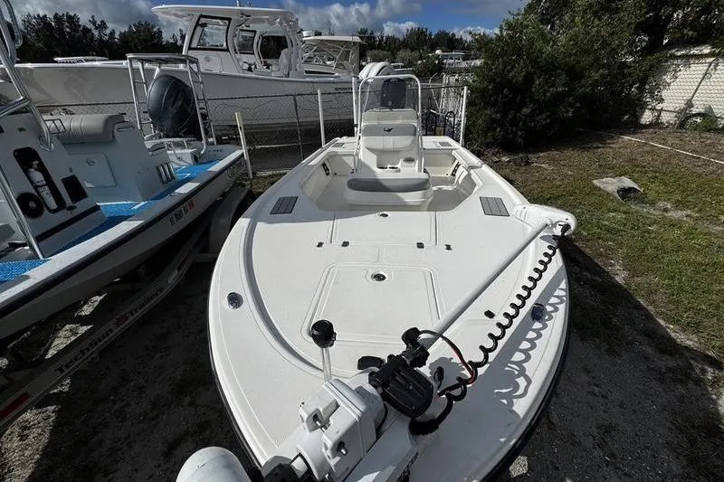 Slide: The Image of 2022 Mako 18 LTS boat, white deck, parked outdoors, surrounded by other boats. - 7