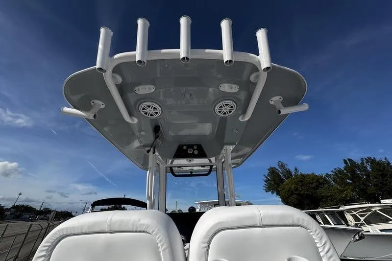 Slide: The Image of 2026 Sportsman Masters 247 Bay Boat with rod holders and speakers under a clear blue sky. - 20