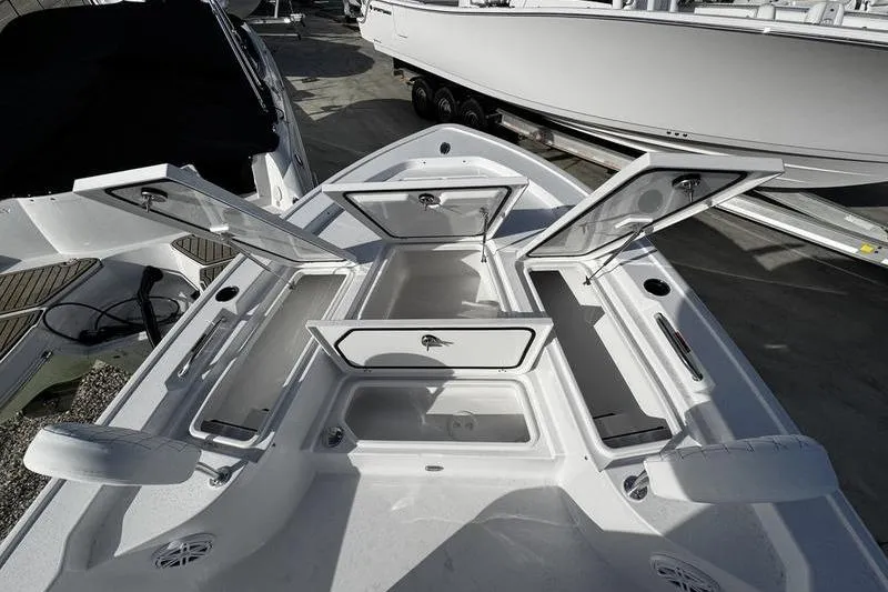 Slide: The Image of 2026 Sportsman Masters 247 Bay Boat with open storage compartments, docked outdoors. - 7