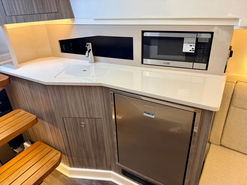 Slide: The Image of The 2026 Sea Ray Sundancer 370 galley features a sink, microwave, and refrigerator. - 26