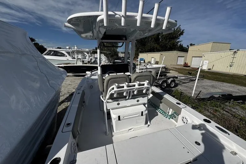 Slide: The Image of 2025 Sportsman Masters 227 Bay Boat deck with fishing equipment, parked among other boats. - 5