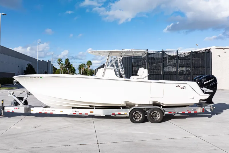 Slide: The Image of 2021 SeaVee 322Z boat on trailer, parked outdoors under a blue sky. - 2