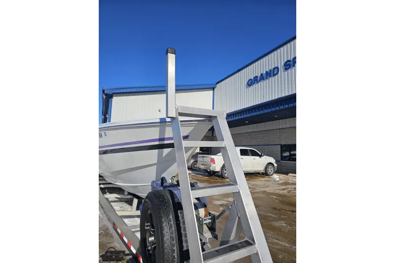 Slide: The Image of 2001 Baja 36 Outlaw boat on trailer outside dealership, clear blue sky. - 13