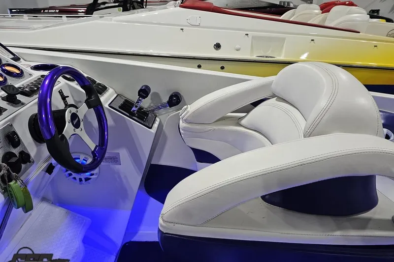 Slide: The Image of Interior of a 2001 Baja 36 Outlaw boat with illuminated controls and white seating. - 57
