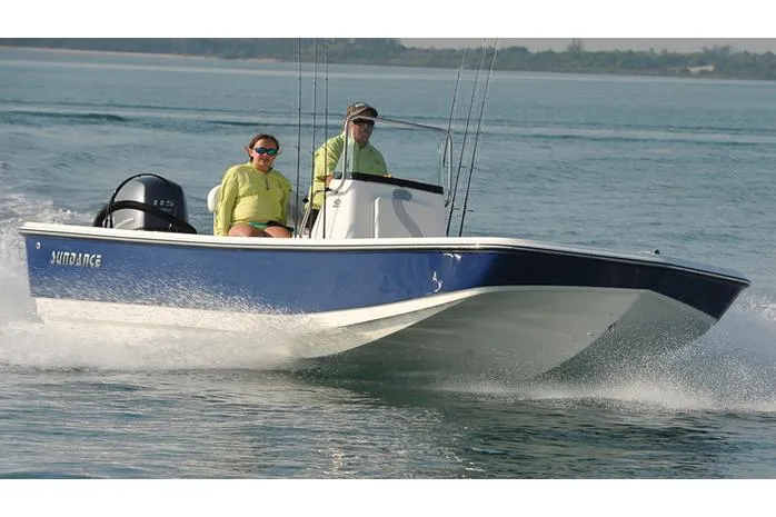 Slide: The Image of Manufacturer Provided Image: 2025 Sundance DX20 boat cruising on water with two passengers, bridge in background. - 3
