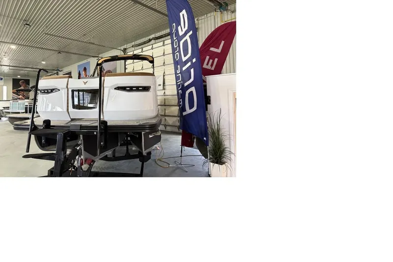 Slide: The Image of 2026 Revel RS25 boat displayed indoors with promotional banners. - 3
