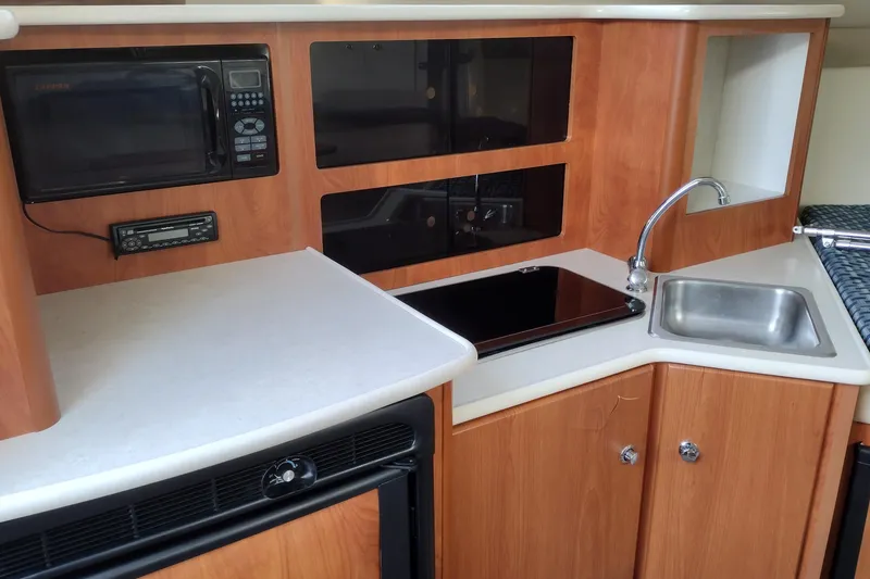 Slide: The Image of 2005 Bayliner 305 boat kitchen with microwave, sink, and stove. - 18