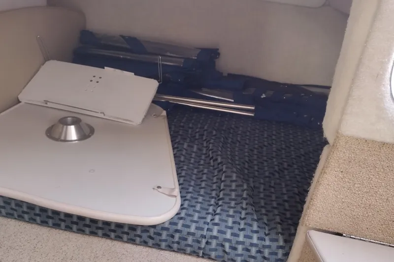 Slide: The Image of 2005 Bayliner 305 interior cabin with folded table and blue patterned seating. - 23