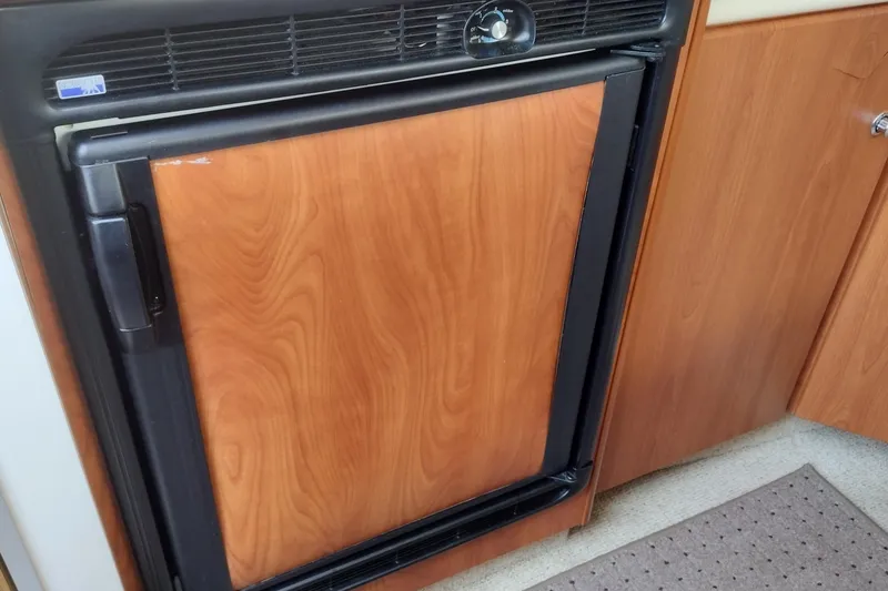 Slide: The Image of 2005 Bayliner 305 boat interior with wood-paneled refrigerator and cabinetry. - 25