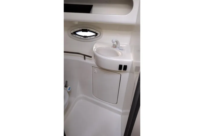Slide: The Image of 2005 Bayliner 305 boat bathroom with sink, cabinet, and porthole window. - 27