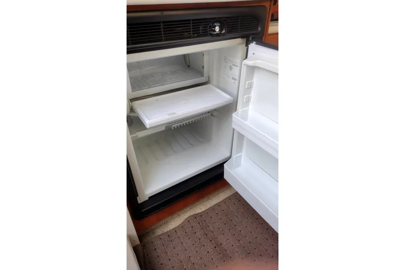 Slide: The Image of Open refrigerator inside a 2005 Bayliner 305 boat, showing empty shelves and door compartments. - 29