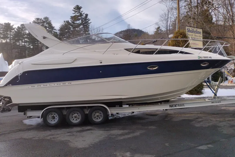 Slide: The Image of 2005 Bayliner 305 boat on trailer at Shoreline Boat Sales, surrounded by trees. - 4