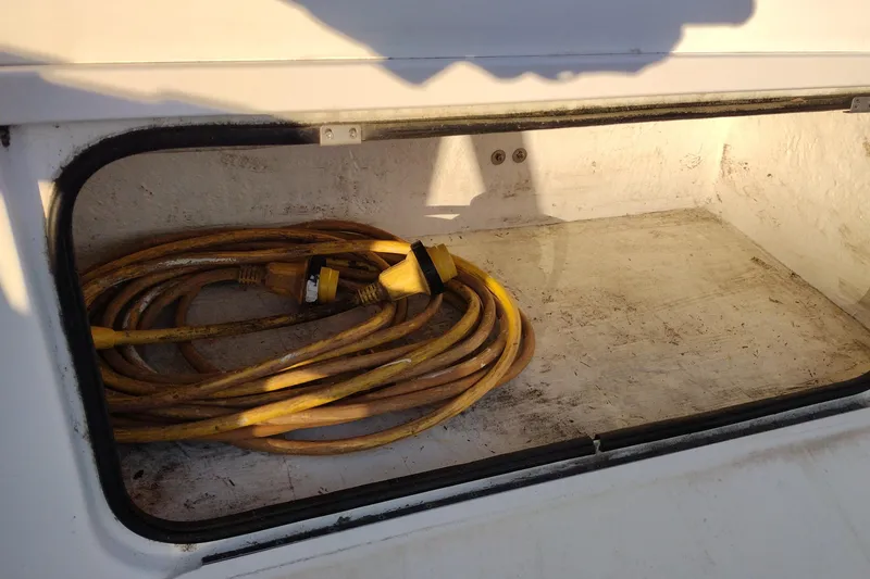 Slide: The Image of Storage compartment of 2005 Bayliner 305 boat with coiled yellow power cable. - 47