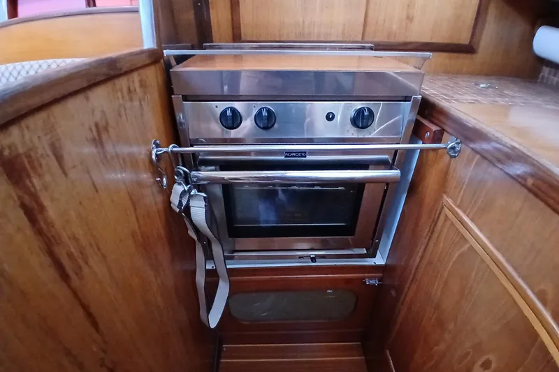 Slide: The Image of 1983 Wauquiez Hood yacht kitchen with stainless steel oven and wooden cabinetry. - 11