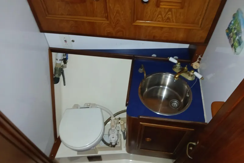 Slide: The Image of 1983 Wauquiez Hood yacht bathroom with sink and toilet, featuring wooden cabinetry. - 18