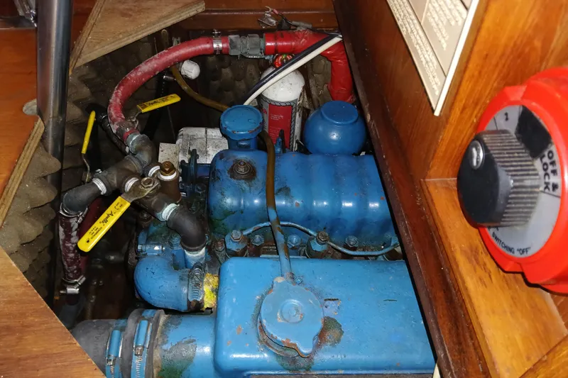 Slide: The Image of Engine compartment of a 1983 Wauquiez Hood sailboat, featuring blue machinery and red hoses. - 30