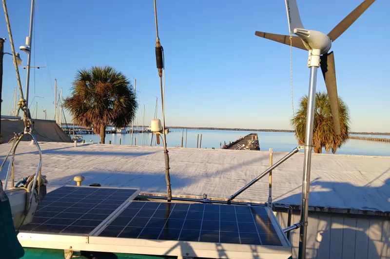Slide: The Image of Sailboat with solar panels and wind turbine, Wauquiez Hood 1983, docked near palm trees. - 37