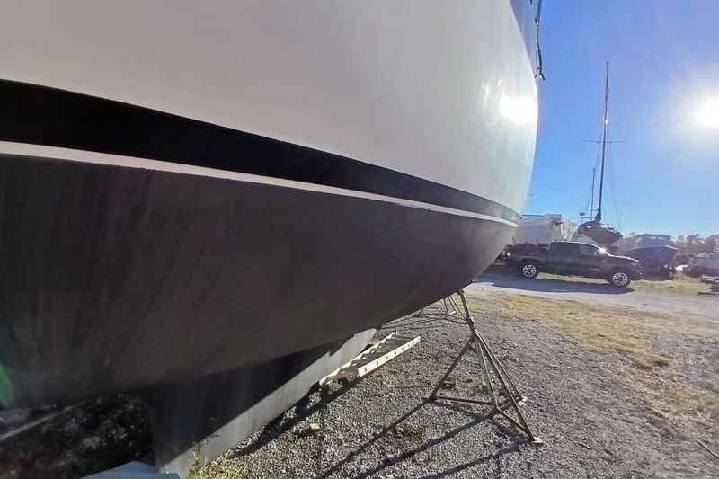 Slide: The Image of 1983 Wauquiez Hood sailboat on stands, sunny day, parked vehicles nearby. - 38