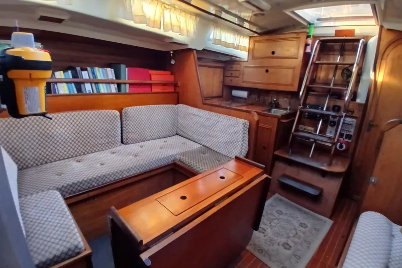 Slide: The Image of 1983 Wauquiez Hood yacht interior with cozy seating, wooden cabinetry, and nautical decor. - 4