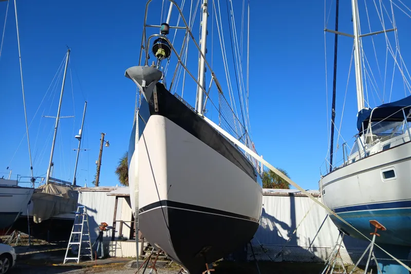 Slide: The Image of 1983 Wauquiez Hood sailboat on land, surrounded by other boats, under clear blue sky. - 41