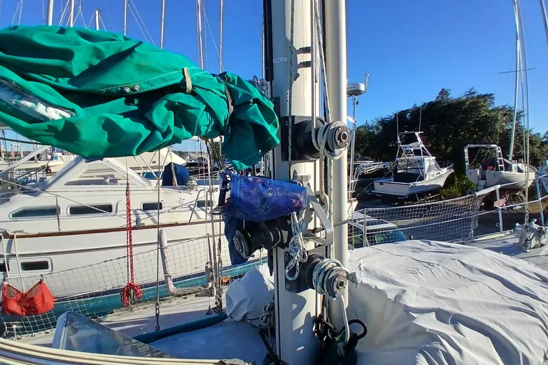 Slide: The Image of 1983 Wauquiez Hood sailboat with green sail cover, docked in a marina under clear blue sky. - 45