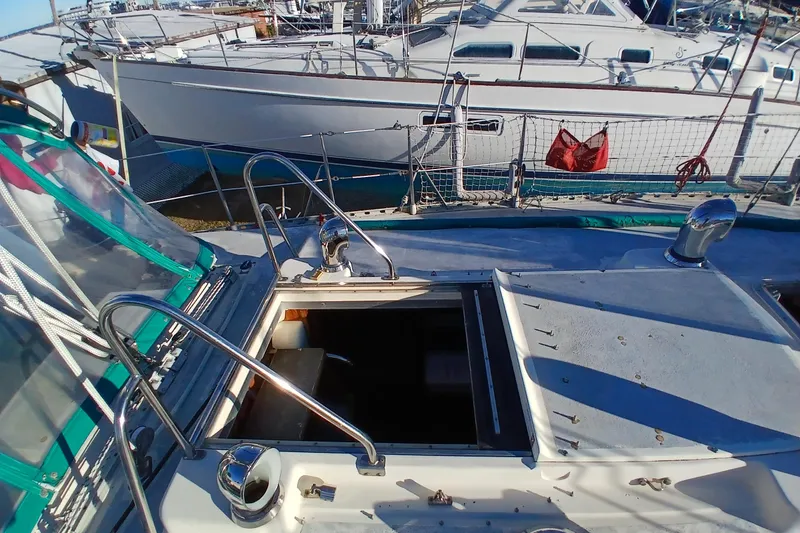 Slide: The Image of 1983 Wauquiez Hood sailboat deck with open hatch, docked alongside other boats. - 46