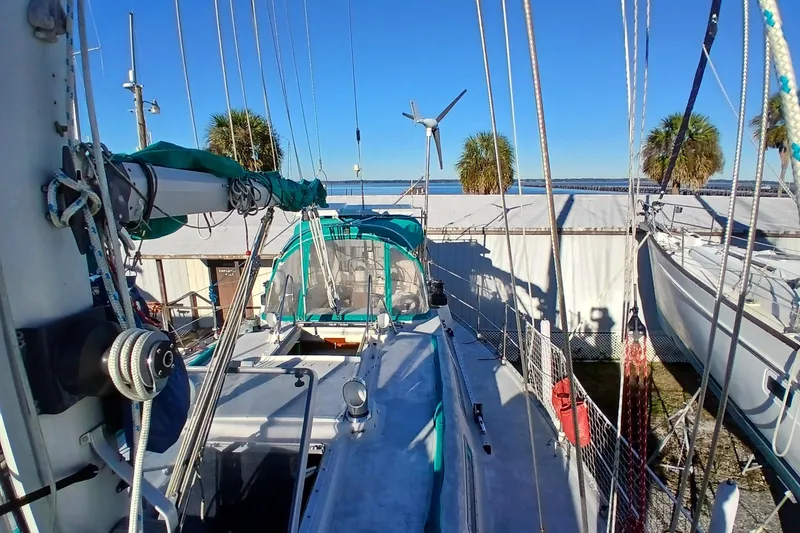 Slide: The Image of 1983 Wauquiez Hood sailboat docked, featuring rigging and a clear blue sky backdrop. - 50
