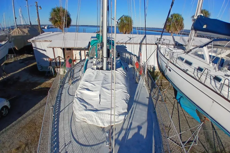 Slide: The Image of 1983 Wauquiez Hood sailboat on land, surrounded by other boats, under clear blue sky. - 51