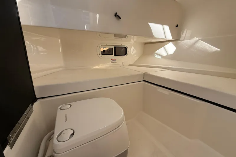 Slide: The Image of 2022 Sea Ray SDX 250 boat interior with compact toilet and storage area. - 10