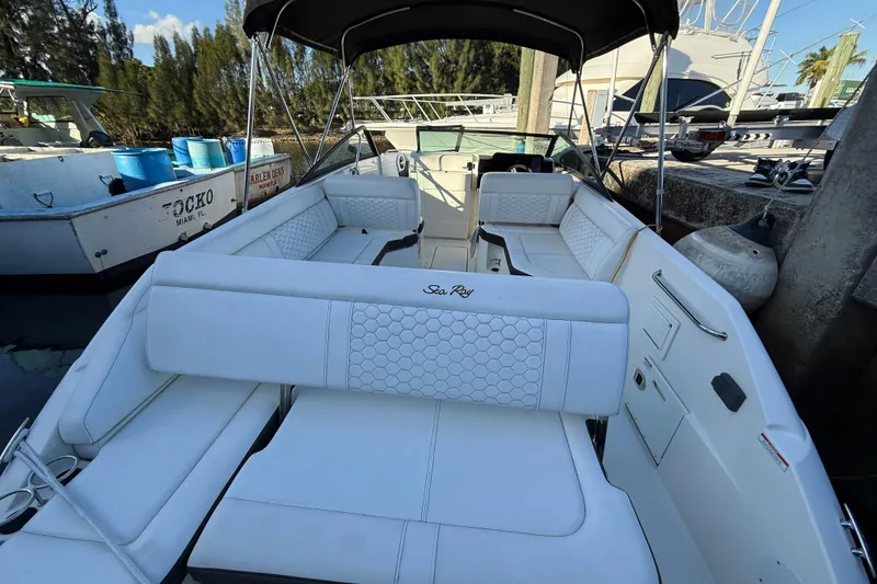 Slide: The Image of 2022 Sea Ray SDX 250 boat with spacious white seating and canopy at dock. - 6