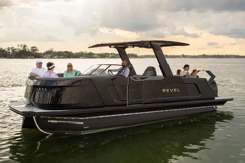 Slide: The Image of Manufacturer Provided Image: 2026 Revel RS25L luxury pontoon boat on a serene lake with passengers enjoying the ride. - 13