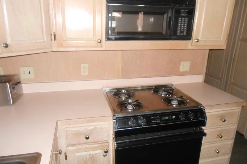 Slide: The Image of 1991 Stardust Cruisers 7516 kitchen with stove, microwave, and light wood cabinets. - 10