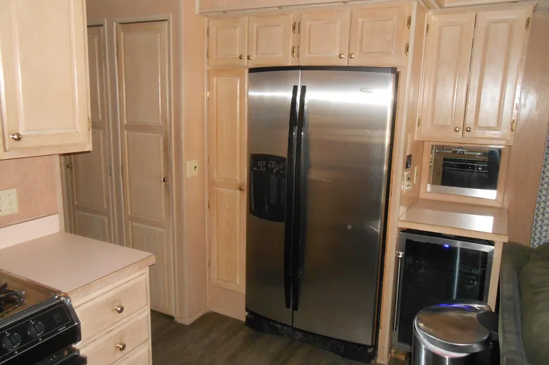 Slide: The Image of Kitchen interior of 1991 Stardust Cruisers 7516 with stainless steel appliances and wooden cabinetry. - 11