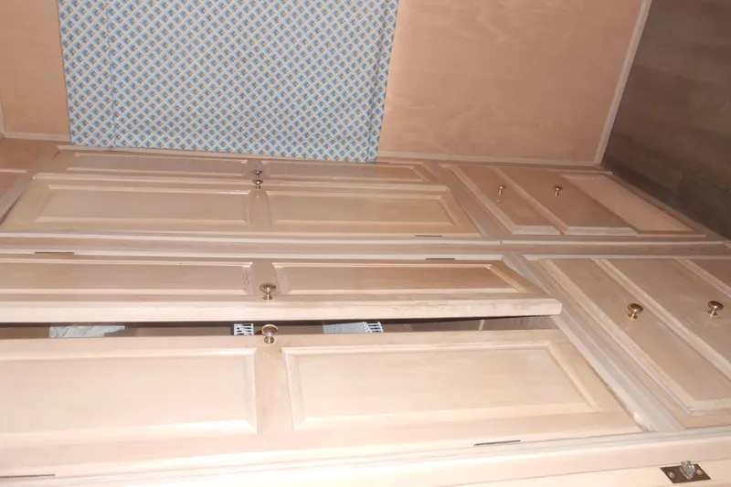 Slide: The Image of Wooden cabinets inside a 1991 Stardust Cruisers 7516, featuring brass knobs and patterned panel. - 23