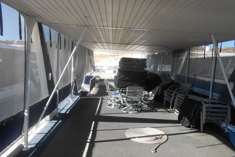 Slide: The Image of 1991 Stardust Cruisers 7516 houseboat interior with stacked chairs and coiled rope. - 29