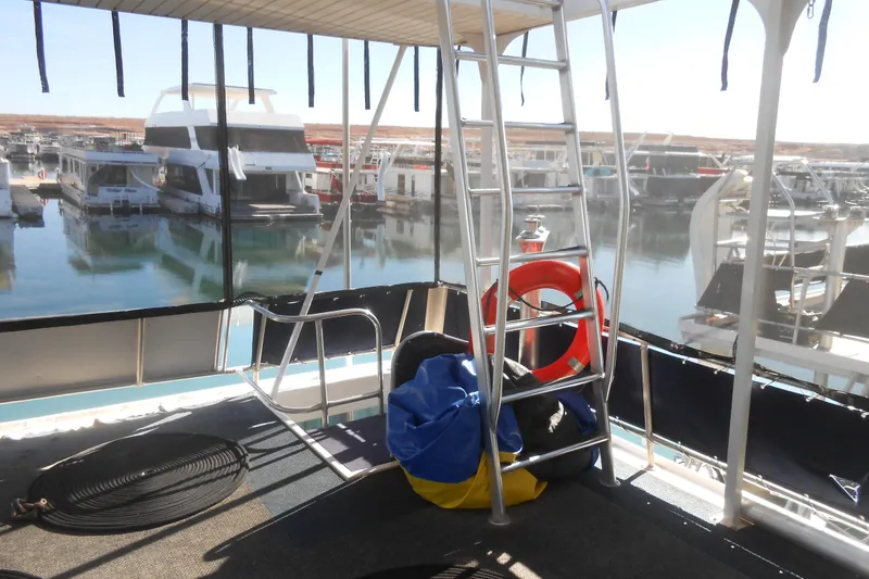 Slide: The Image of 1991 Stardust Cruisers 7516 houseboat interior with marina view, featuring ladder and life preserver. - 31