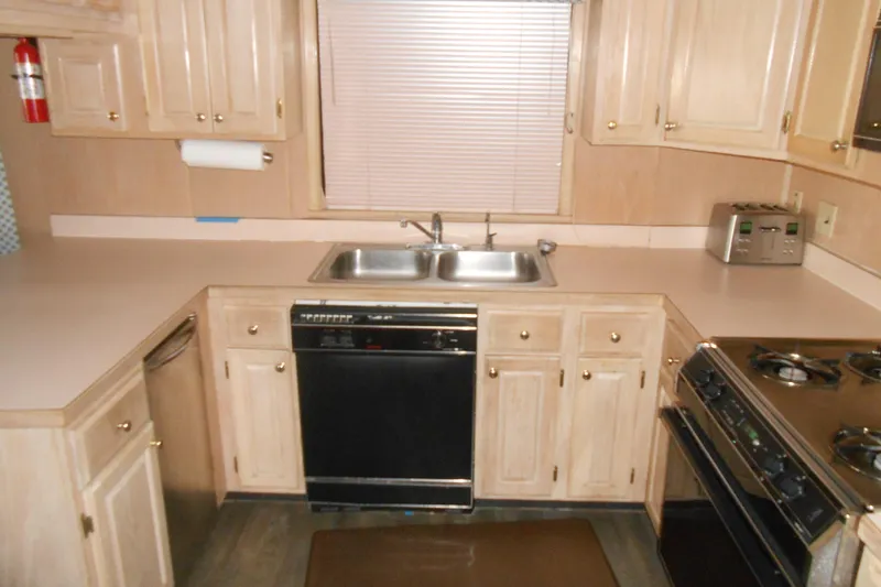 Slide: The Image of 1991 Stardust Cruisers 7516 kitchen with wooden cabinets, double sink, and appliances. - 9