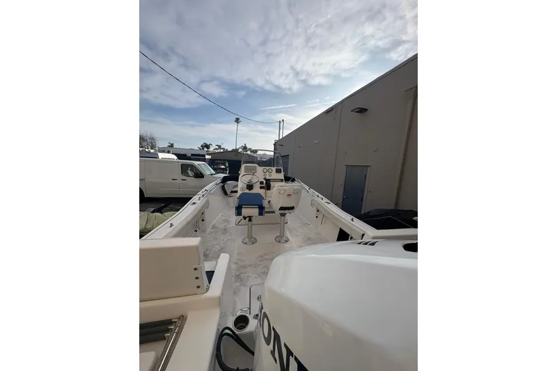 Slide: The Image of 2021 Tidewater 198 CC Adventure boat interior with console and seating under cloudy sky. - 14