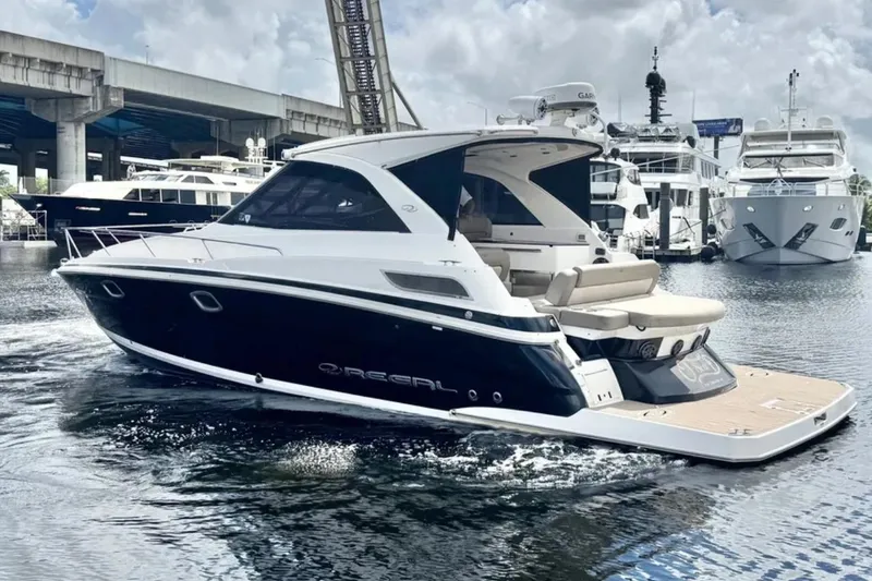 Slide: The Image of 2015 Regal 35 Sport Coupe yacht cruising in a marina, surrounded by other boats. - 2