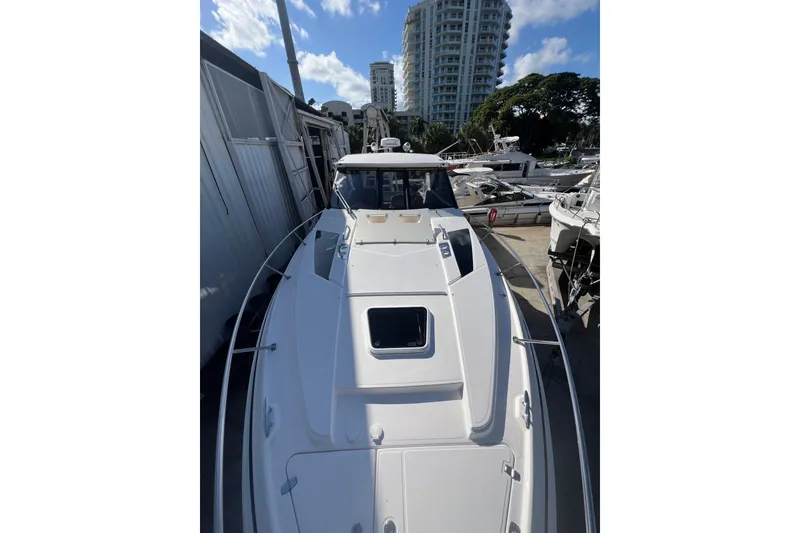 Slide: The Image of 2015 Regal 35 Sport Coupe boat docked near high-rise buildings and trees. - 27