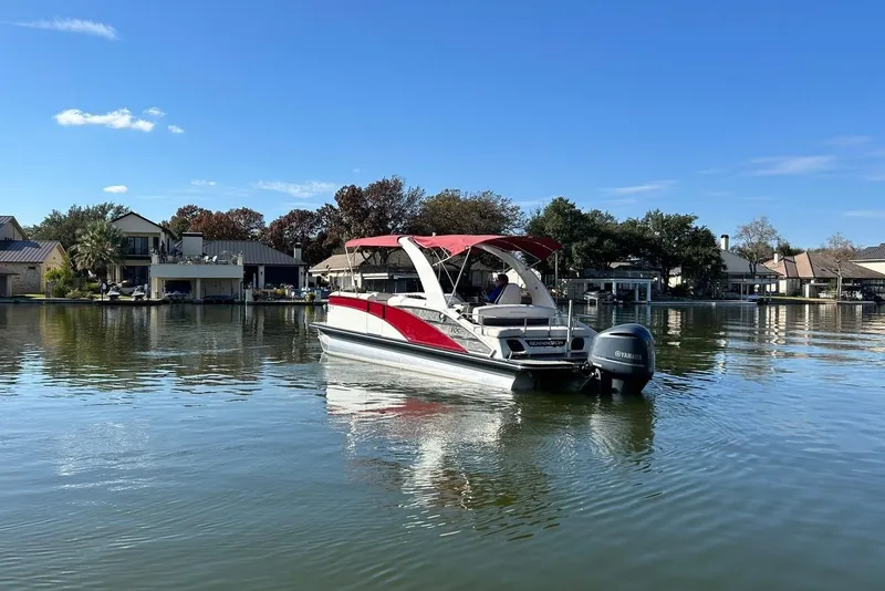 Slide: The Image of 2021 Bennington 25 RXSBA pontoon boat on a calm lake with waterfront homes. - 10