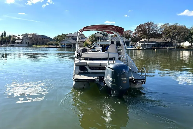Slide: The Image of 2021 Bennington 25 RXSBA pontoon boat on a serene lake with Yamaha 300 engine. - 13