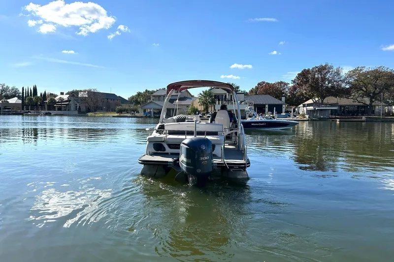 Slide: The Image of 2021 Bennington 25 RXSBA pontoon boat on a serene lake with clear skies. - 14