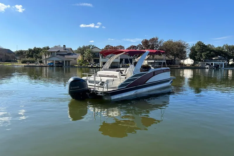 Slide: The Image of 2021 Bennington 25 RXSBA pontoon boat on a calm lake with scenic background. - 16