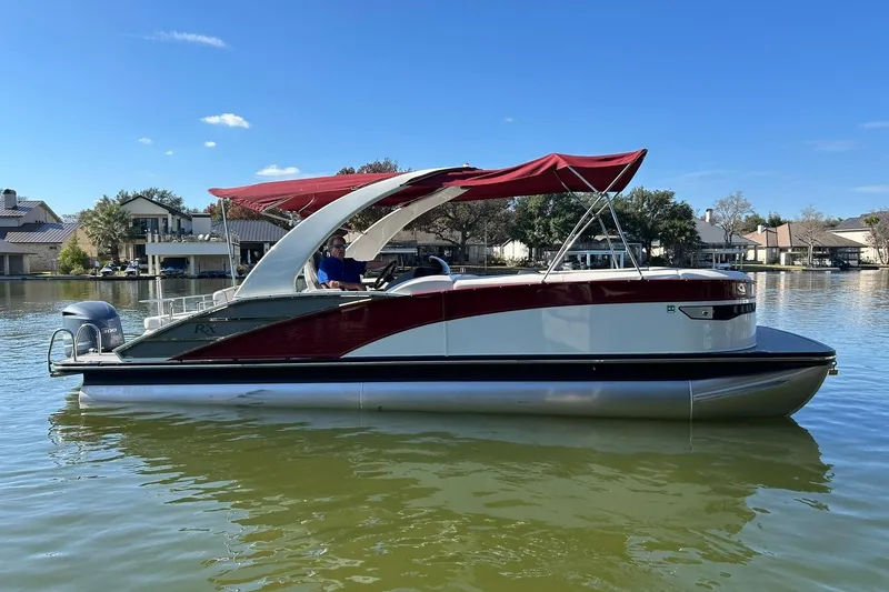 Slide: The Image of 2021 Bennington 25 RXSBA pontoon boat with red canopy on a calm lake. - 17