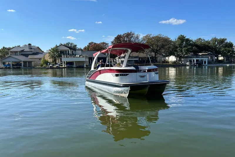Slide: The Image of 2021 Bennington 25 RXSBA pontoon boat cruising on a serene lake. - 20