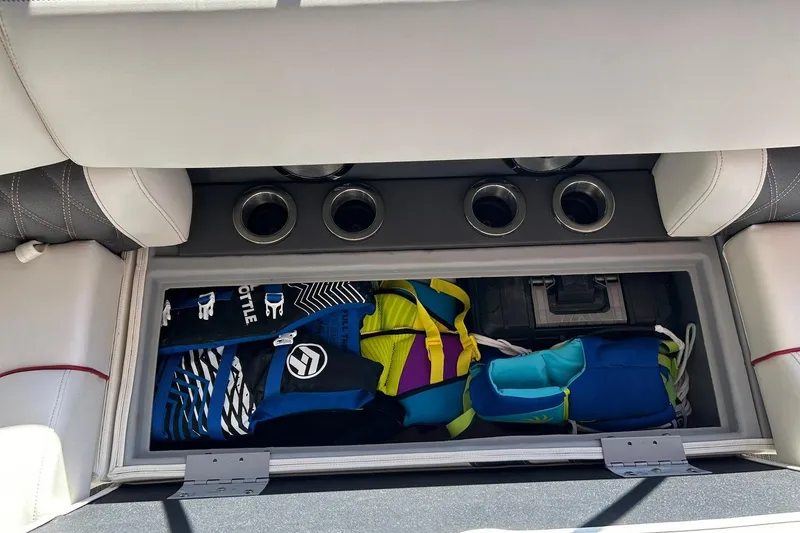 Slide: The Image of 2021 Bennington 25 RXSBA boat storage compartment with life jackets and cup holders. - 54