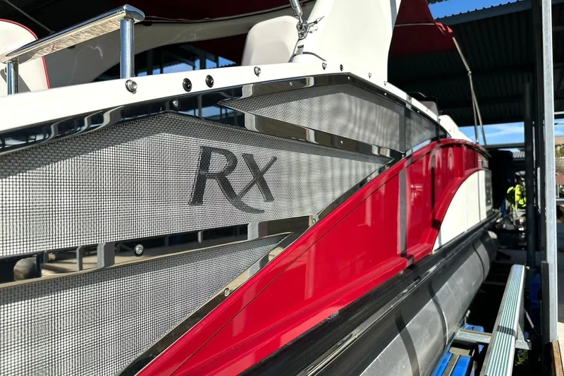 Slide: The Image of 2021 Bennington 25 RXSBA pontoon boat with red and silver detailing in a marina. - 58