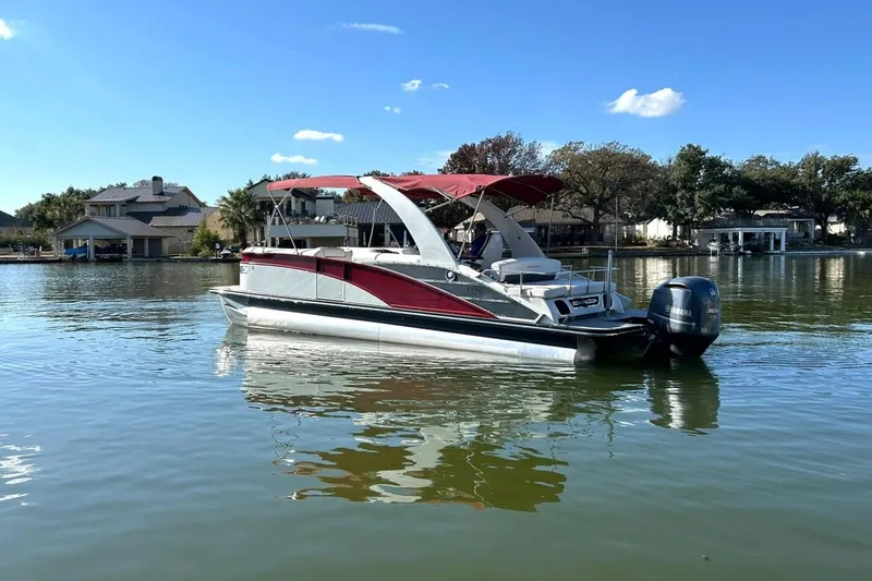 Slide: The Image of 2021 Bennington 25 RXSBA pontoon boat on a calm lake under a clear blue sky. - 7