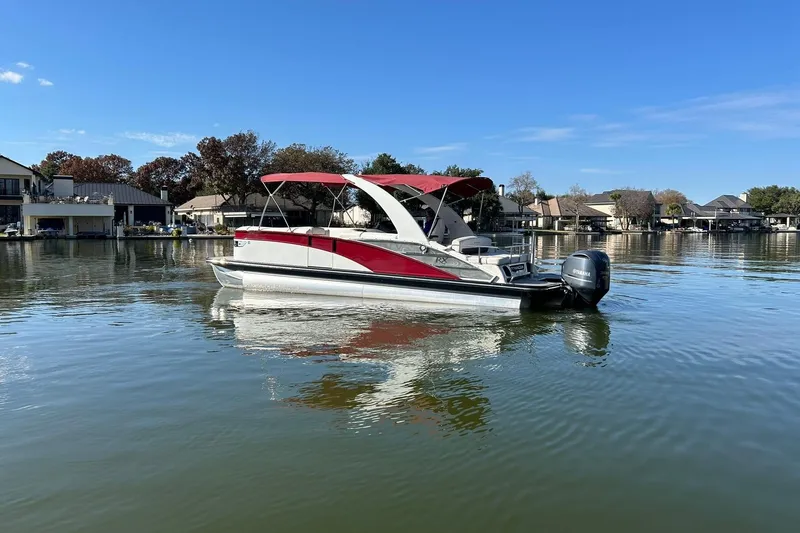 Slide: The Image of 2021 Bennington 25 RXSBA pontoon boat on a calm lake with red canopy. - 8